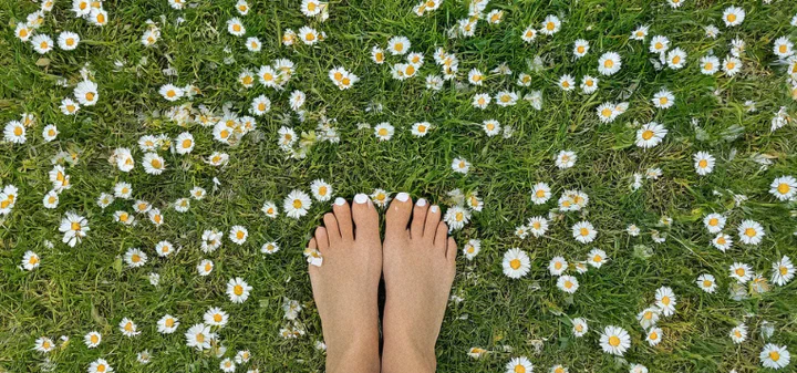 Person walking barefoot on grass demonstrating grounding/earthing practice